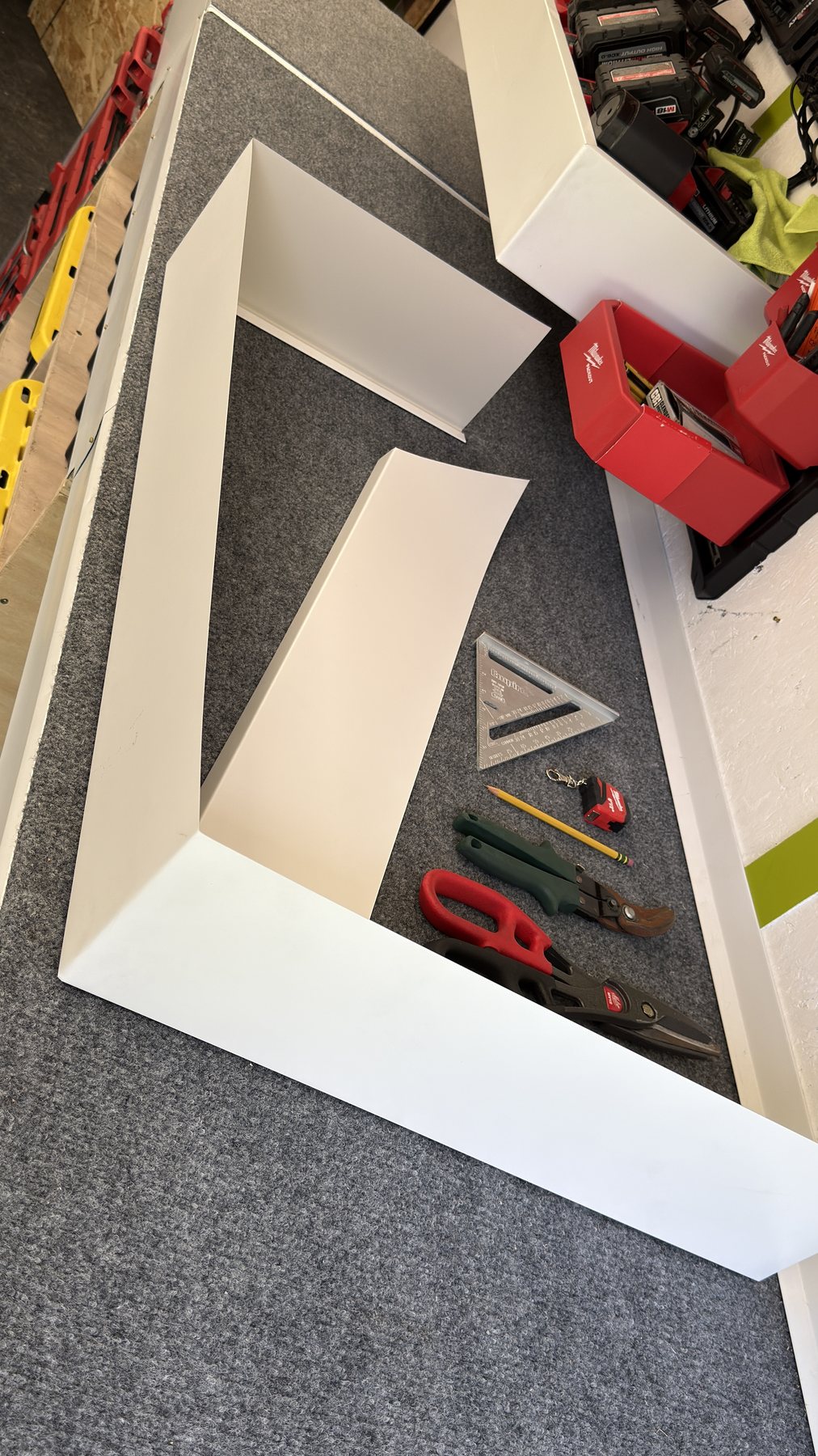 Bent aluminum pieces on the trailer workbench with snips, a speed square and a tape measure
