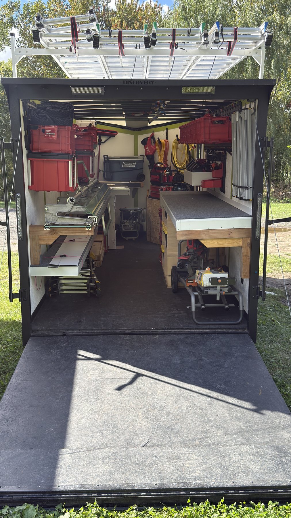 Open Rambow Exteriors trailer showing the sheet metal brake, workbench and ladders racked on top