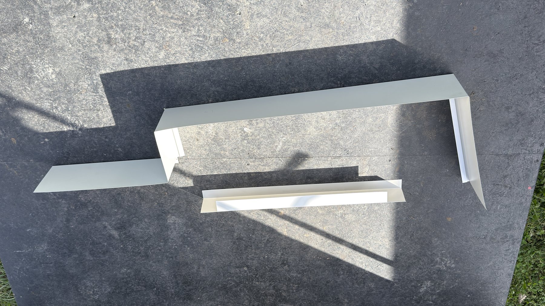 Custom-bent white aluminum trim pieces laid out on the trailer ramp