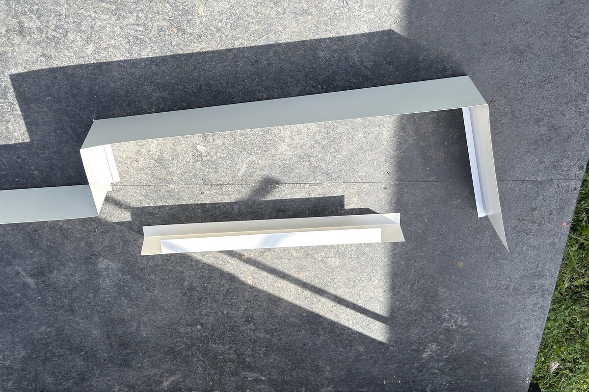 Custom-bent white aluminum trim pieces laid out after bending
